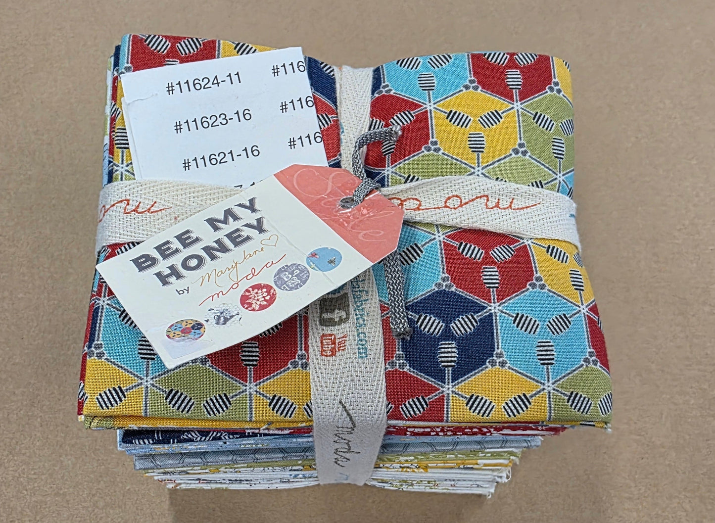 Stack of colorful fabric squares with labels on a brown surface