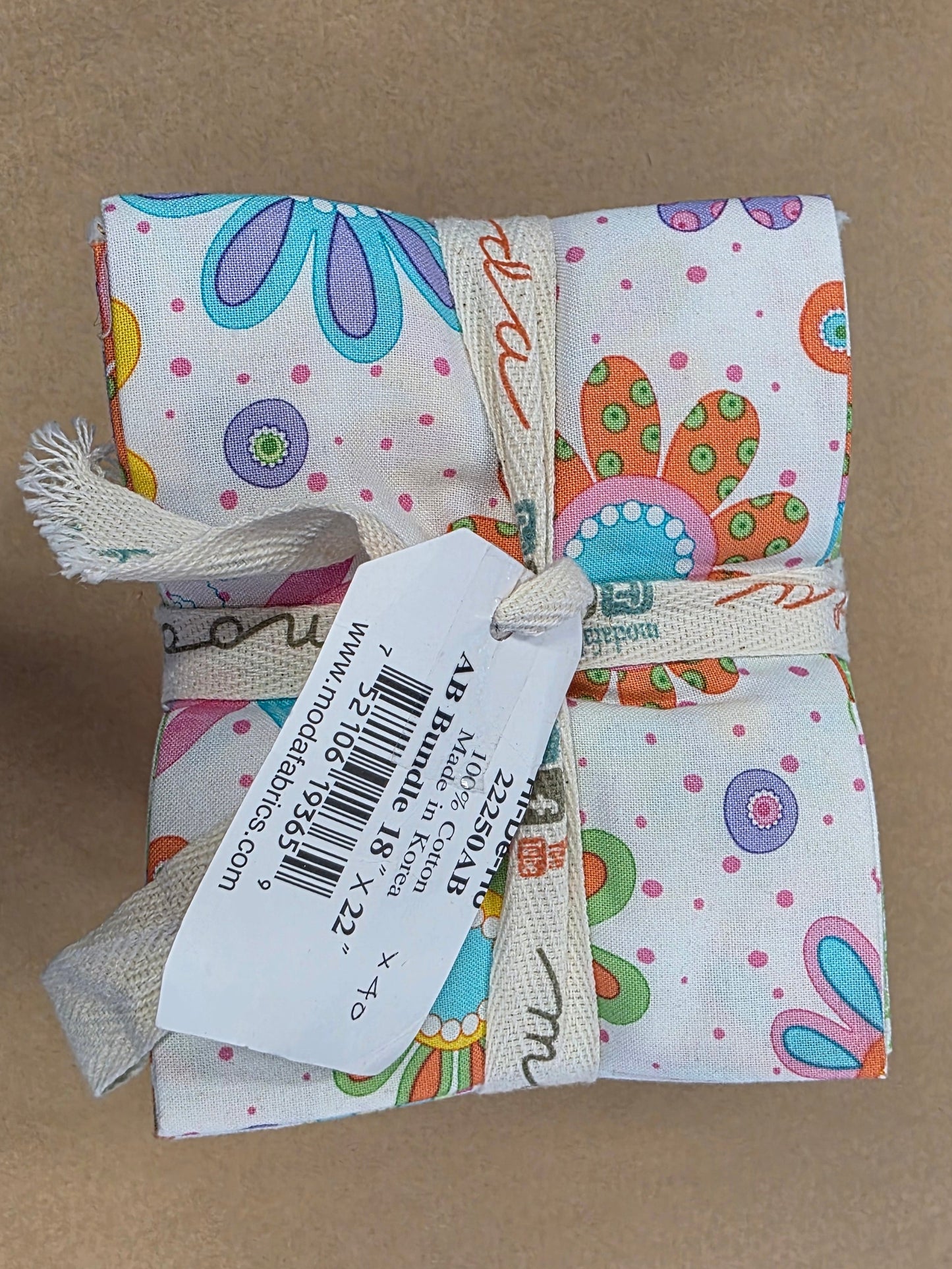 Pack of colorful fabric bundles tied with a ribbon on a brown surface